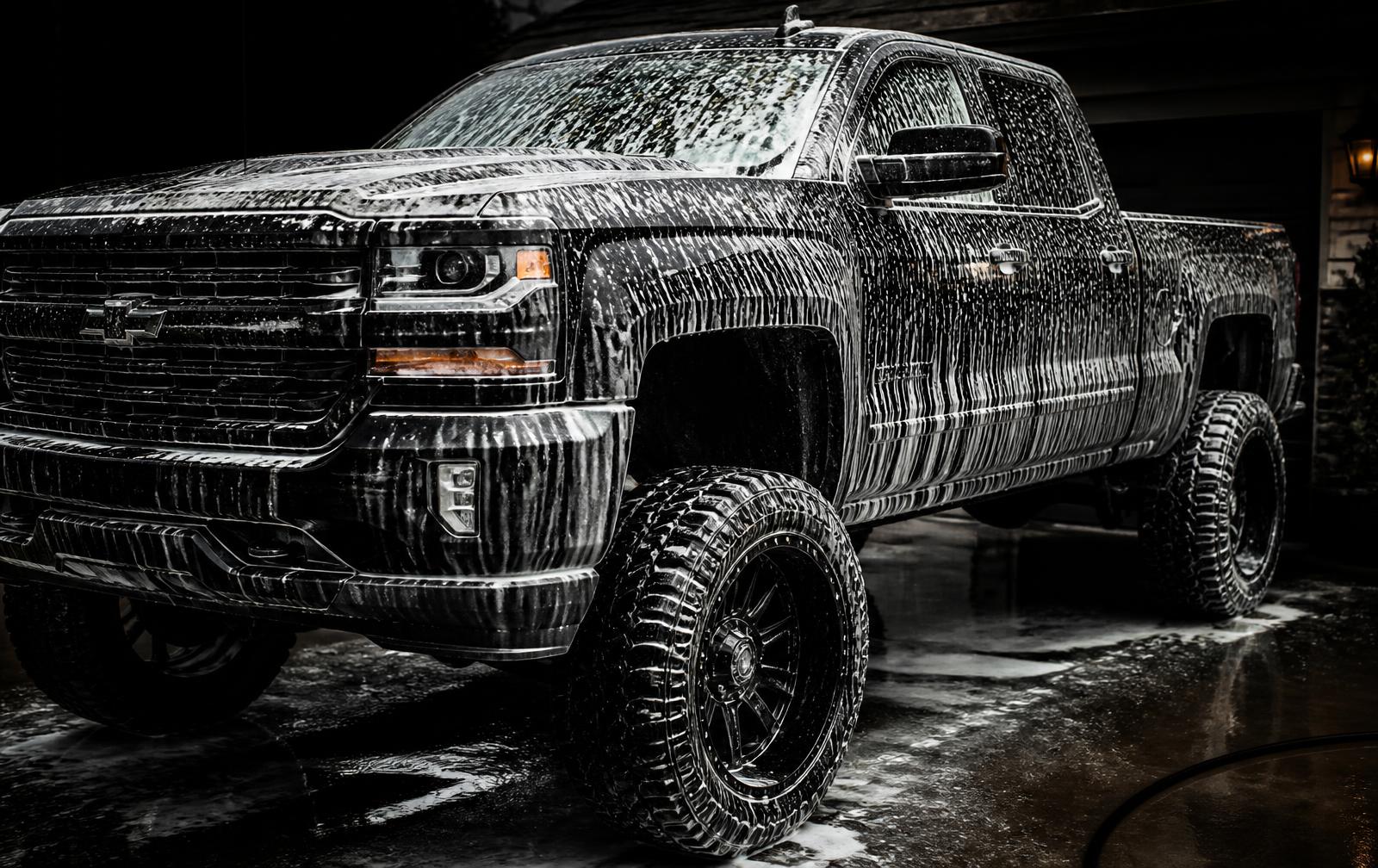 Black pickup truck covered in foam during a mobile detail